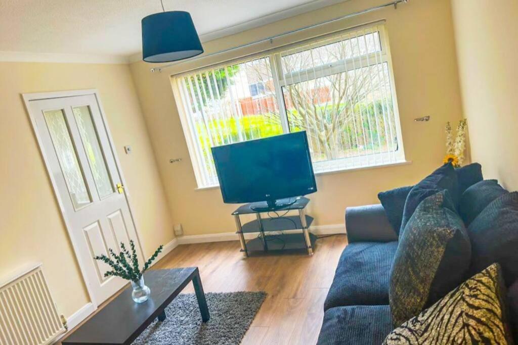 a living room with a blue couch and a flat screen tv at Lovely 3 Bed with Free parking-Families, Professionals and Contractors Welcome in Luton