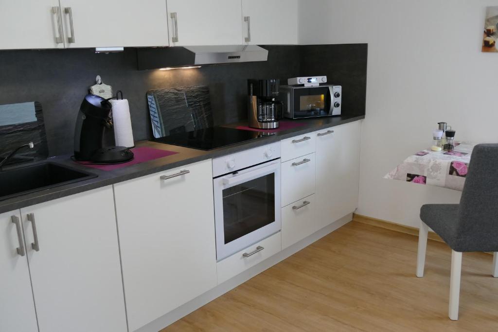 Breidenbach的住宿－Zum Wiesengrund Blecher，厨房配有白色橱柜和黑色台面
