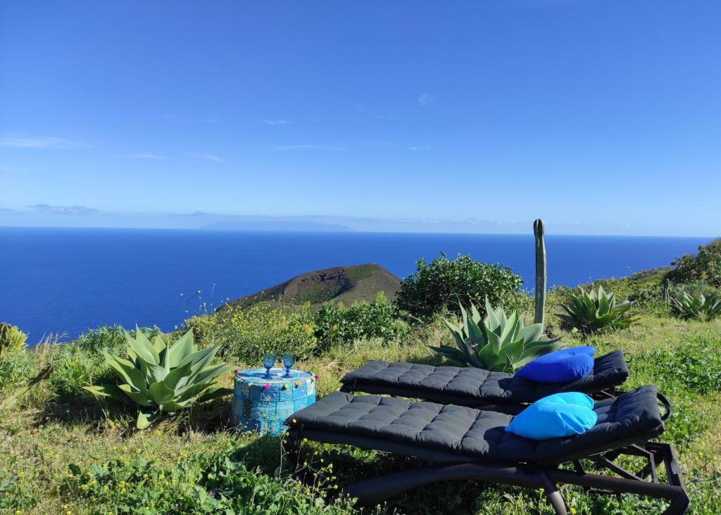 Nature Finca Apartment - Pure Relaxation في Mazo: مقعد جالس على قمة تل مطل على المحيط