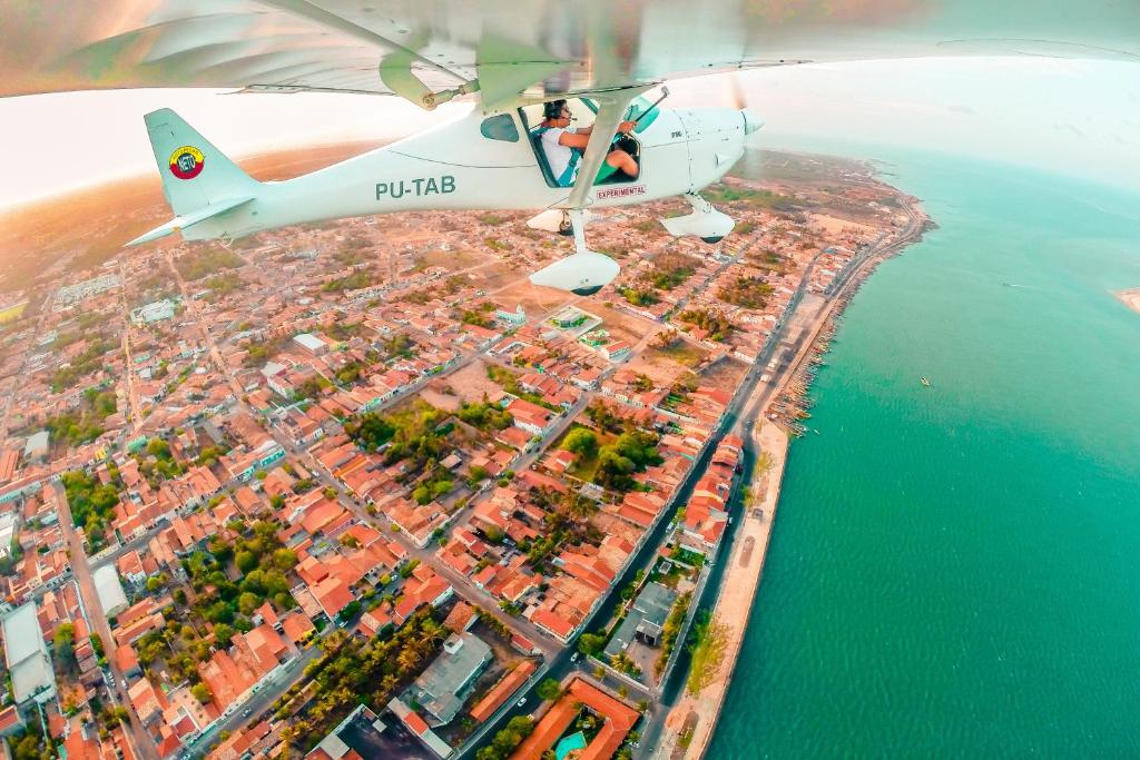 a plane flying over a city and the ocean at Hotel Pinto Martins in Camocim