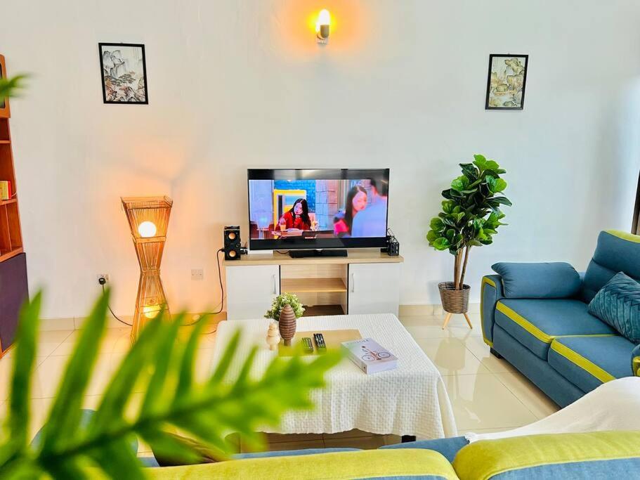 sala de estar con sofá azul y TV en Laksamana Gathering Homestay BP en Batu Pahat