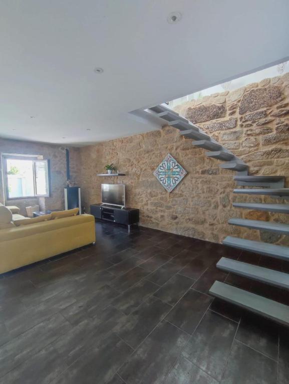 een woonkamer met een trap en een bakstenen muur bij Agarimo Home in Virxe das Mareas