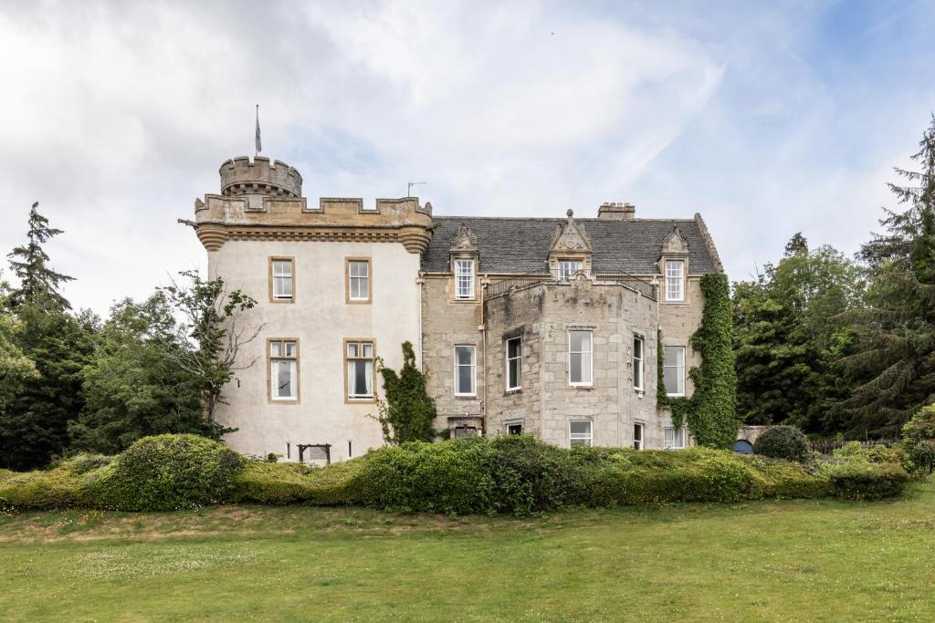 un ancien château avec une tour au-dessus d'un champ dans l'établissement Tulloch Castle Hotel ‘A Bespoke Hotel’, à Dingwall