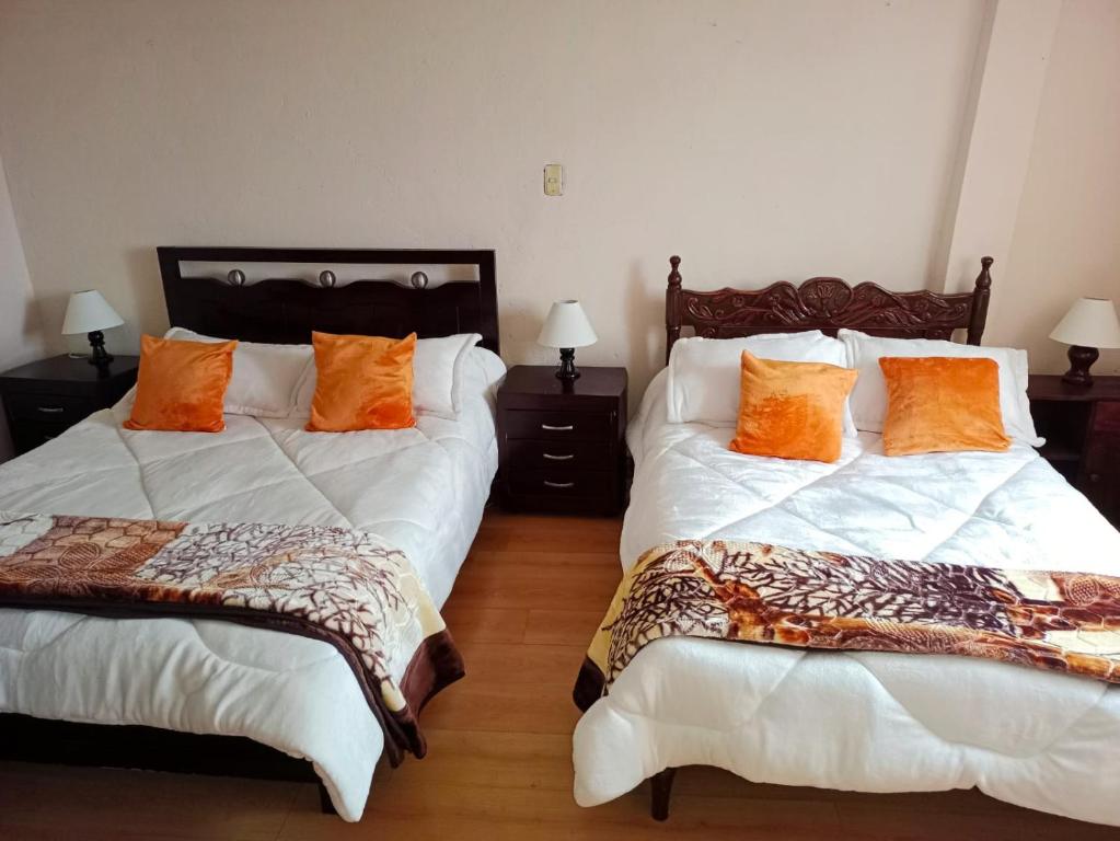 um quarto com 2 camas com almofadas laranja em Casa Rural Zaba Lago de Tota em Aquitânia