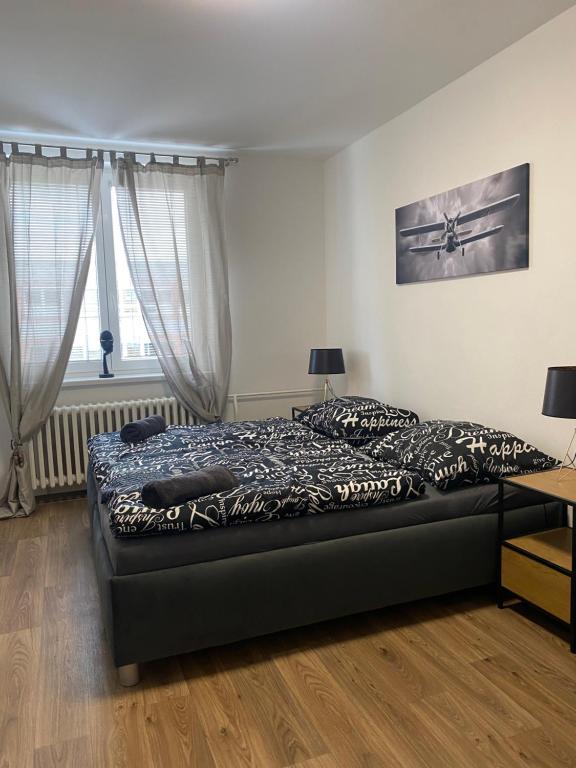 a bedroom with a bed and a desk and two windows at Černá růže - Apartmán 3 in Plzeň