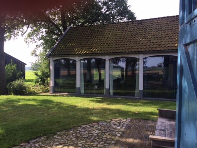 a house with a porch with a bench in a yard at Koetshuis in Veenhuizen
