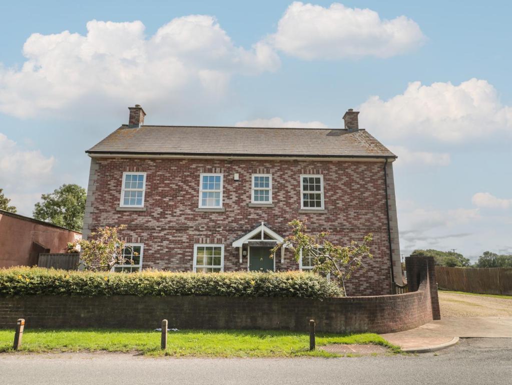 uma grande casa de tijolos com uma cerca em frente em Cherry Tree House em Highbridge