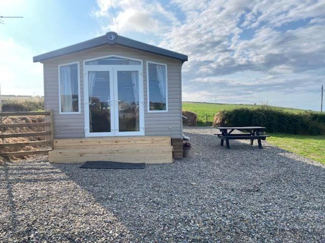 a small shed with a picnic table and a bench at Mwnt Sea View Caravan with Free WiFi in Cardigan