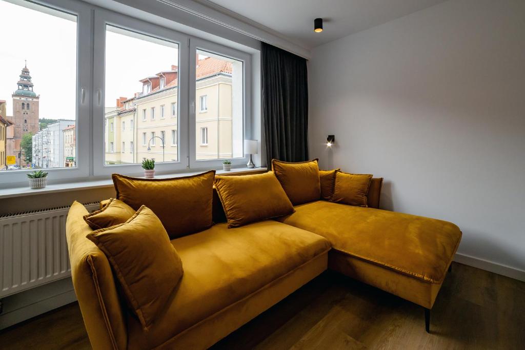 żółtą kanapę w pokoju z oknami w obiekcie Apartament Alpaka 2 w Lidzbarku Warmińskim
