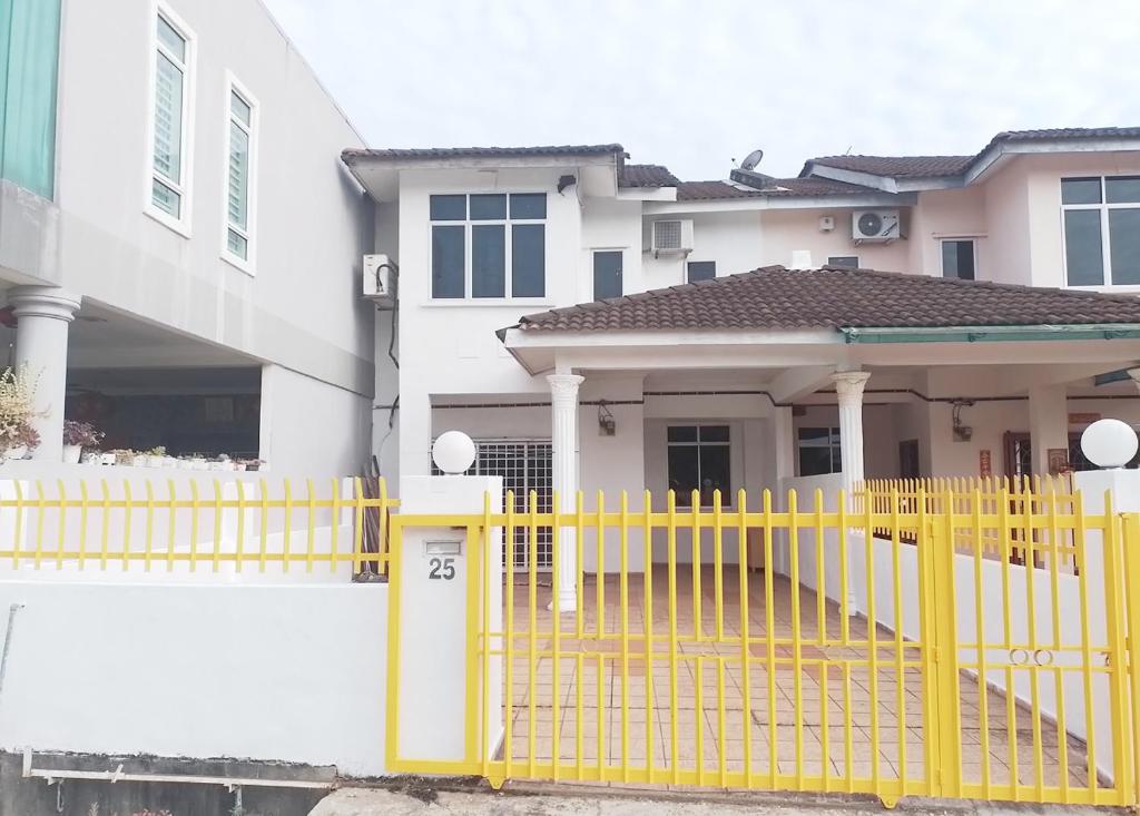 een geel hek voor een wit huis bij Welcome to Gemas Homestay ALI 