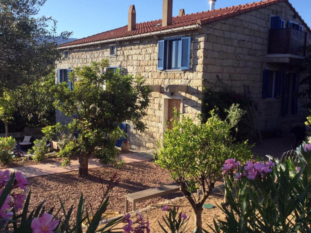 a stone house with a garden in front of it at Le moulin de Figari, oil mill & pool in Figari