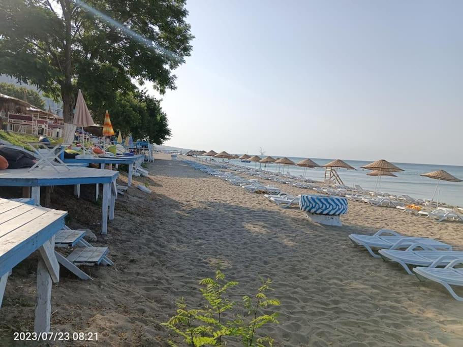 a beach with picnic tables and chairs and the ocean at Kumburgaz Sahilde, Sitede, Konforlu, Manzaralı Klimalı Daire in Buyukcekmece