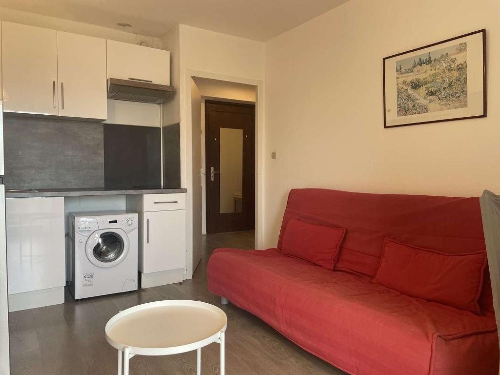 un salon avec un canapé rouge et une cuisine dans l'établissement Juan les Pins: Appartement 2 pièces avec piscine proche plage - FR-1-252-194, à Antibes