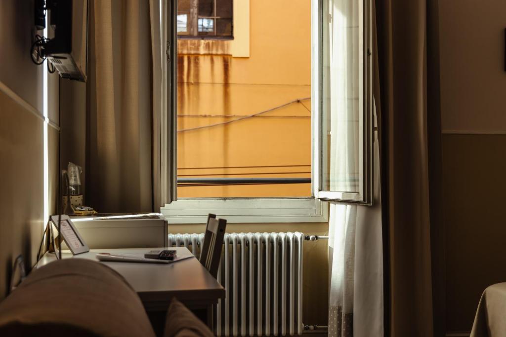 ボローニャにあるIl Tiro Roomsの窓、テーブル、ラジエーターが備わる客室です。