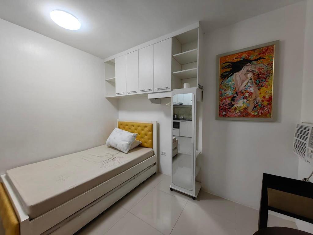 Dormitorio pequeño con cama y nevera en Hardrock Residences en Cabanatuan