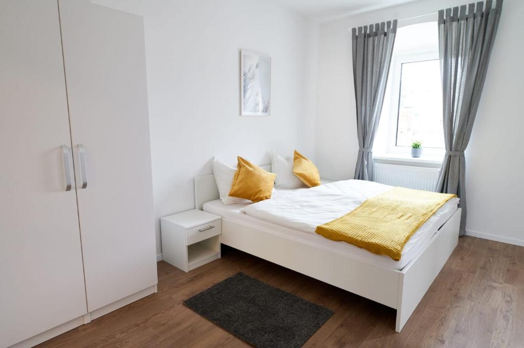 a white bedroom with a bed and a window at WeinlandMotel in Ebenthal