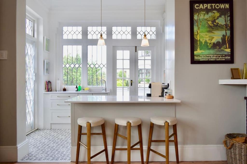 una cocina con encimera blanca y taburetes en Spacious 3 Bedroom Home Green Point, en Ciudad del Cabo