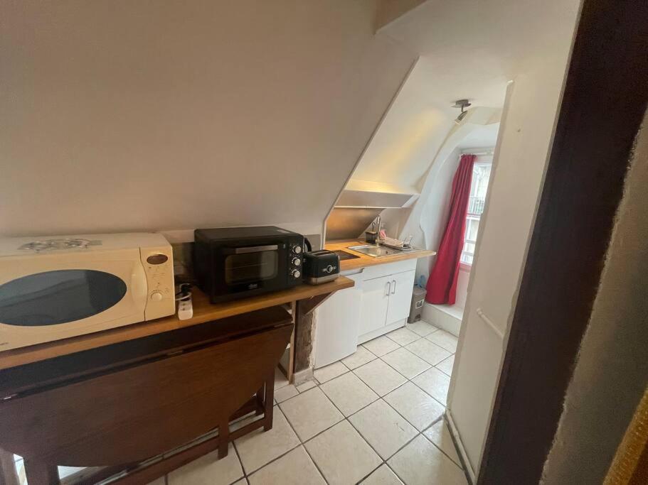 a small kitchen with a microwave on a counter at Jupiter 3 YourHostHelper in Caen