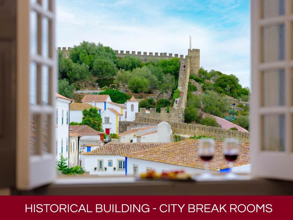 a view of a city from a window with wine glasses at Casa Senhoras Rainhas AL - Obidos - by Unlock Hotels in Óbidos