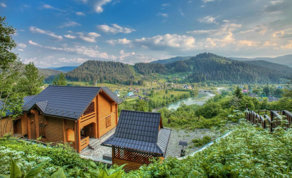 a wooden house with a solar roof and a river at Cottage Goyra in Yaremche