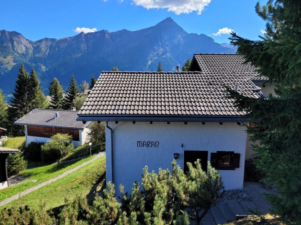 a white house with mountains in the background at Haus Maran in Urmein