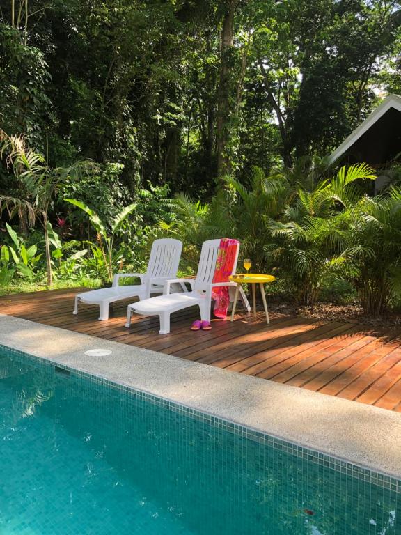 two chairs and a table next to a swimming pool at Villa Wolaba in Puerto Viejo