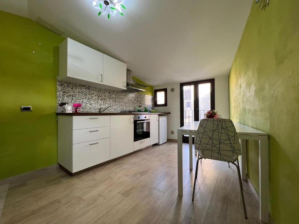 una cocina con armarios blancos y una mesa con una silla en Benvenuti al Sud B&B, en Licata