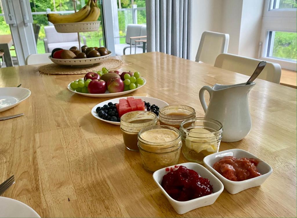 a table with bowls of fruit and jars of jam at Le Camp Caché Shefford in Shefford