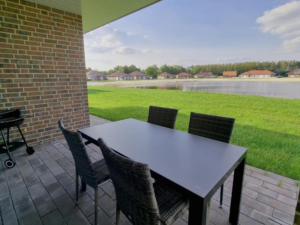 a table and chairs on a patio with a view of a lake at Ferienhaus Seebrise - a90185 in Walchum