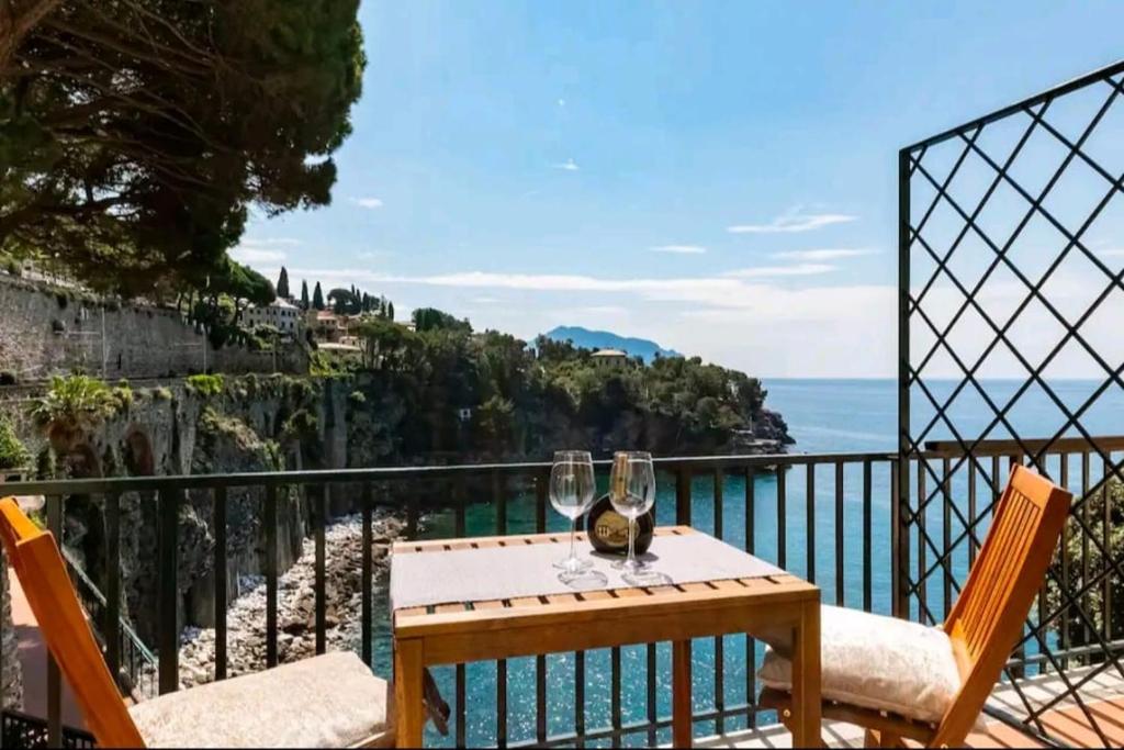 a table with wine glasses on a balcony with the ocean at Pieve Ligure a picco sul mare con piscina Villa Regina in Pieve Ligure