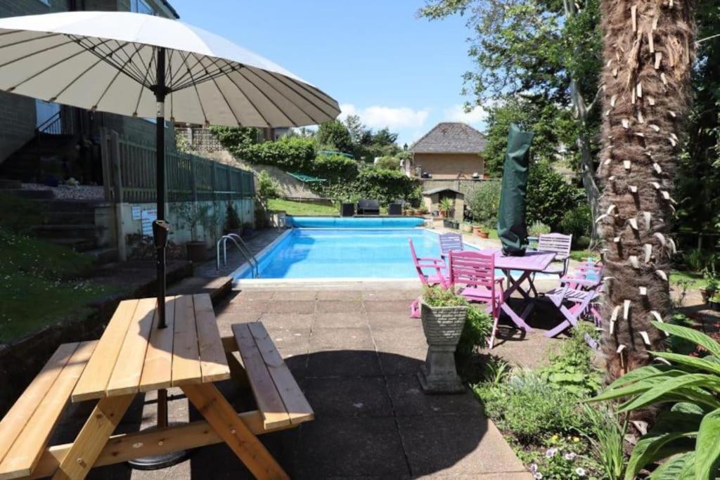 een zwembad met een tafel en een parasol en stoelen bij Beautiful 1-Bedroom Apartment with Pool - Great Ferry offers in Shanklin