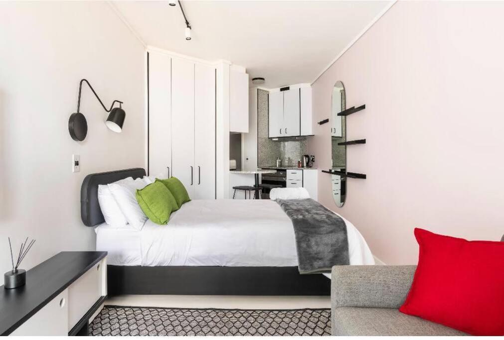 a bedroom with a white bed and a red pillow at Sweet Flamingo in Cape Town