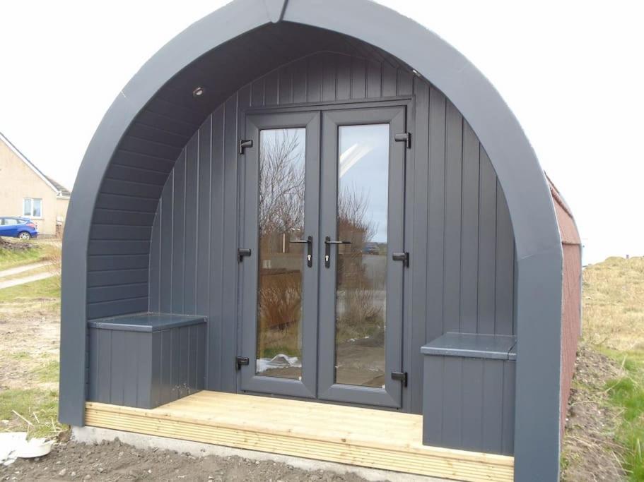 an arched entryway to a shed with a door at Croisgeir Self Catering Pod in Daliburgh