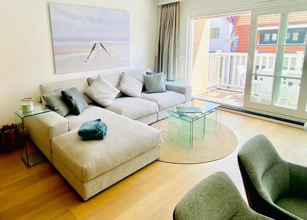 ein Wohnzimmer mit einem Sofa und einem Tisch in der Unterkunft Appartement moderne 2 chambres et grand balcon in Knokke-Heist