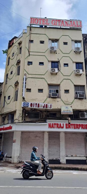 a man riding a motorcycle in front of a building at Hotel Gitanjali in Ahmedabad