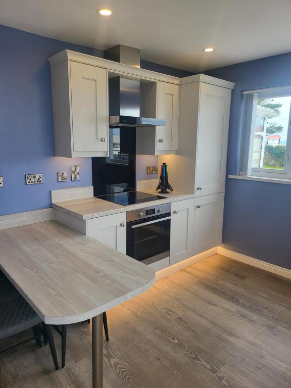 a kitchen with white cabinets and a table in it at Royal Court Hotel in Portrush