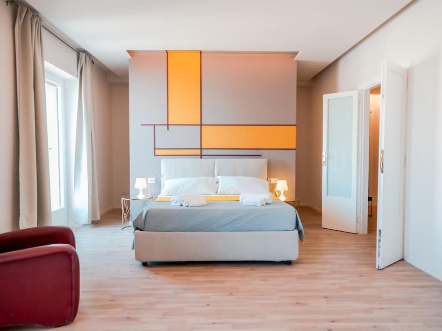 Un dormitorio con una cama grande y una silla roja. en Myosotis luxury apartment, en Siracusa