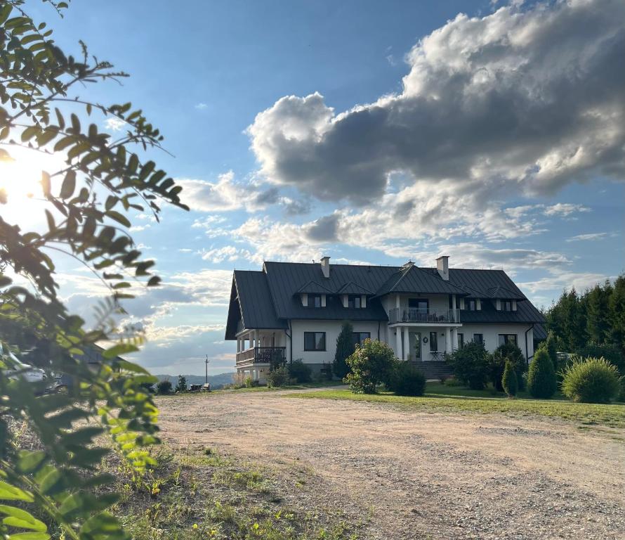 a large white house with a black roof at Cisowe Sioło in Jeleniewo