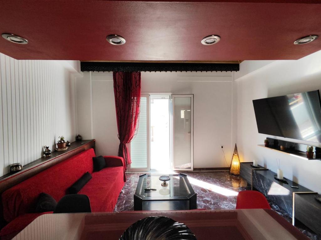 a living room with a red couch and a tv at ~Lovey-Dovey~ nice & central apartment ~Sitia~ in Sitia