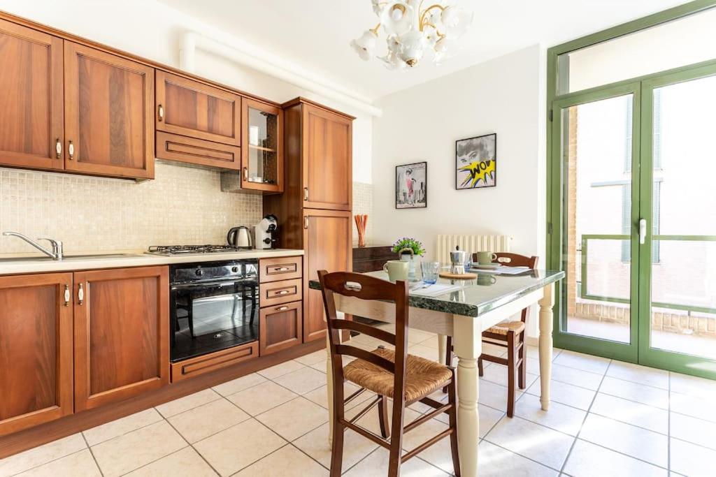 een keuken met houten kasten en een tafel met stoelen bij Casa dei quadri monolocale Jesi in Iesi