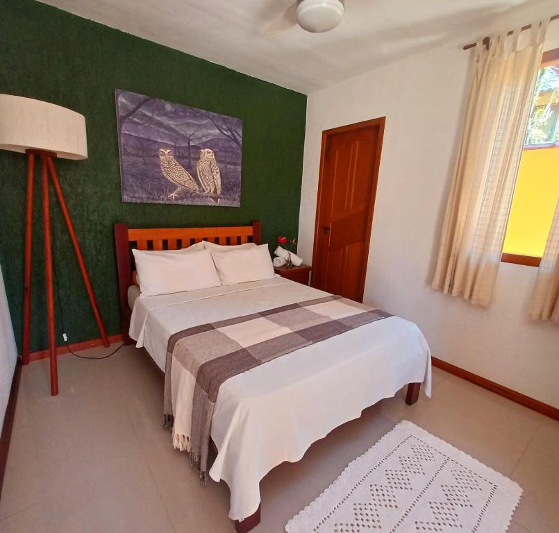 a bedroom with a bed and a green wall at Suítes Estou de Férias Paraty in Paraty