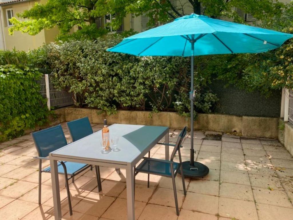 une table et des chaises avec un parapluie bleu dans l'établissement le Signoret, à Aix-en-Provence