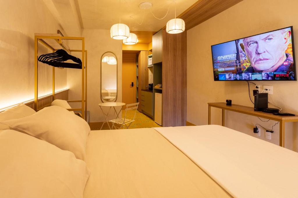 a hotel room with a bed and a flat screen tv at Studio Savana in São Paulo