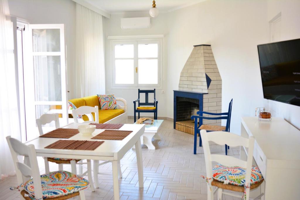 ein Wohnzimmer mit einem Tisch, Stühlen und einem Kamin in der Unterkunft Tarmaros Apartments in Sisi