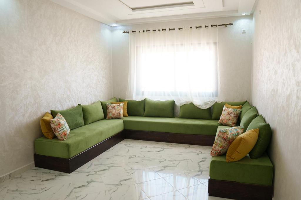 a living room with a green couch and a window at Ayour appartement in Azrou