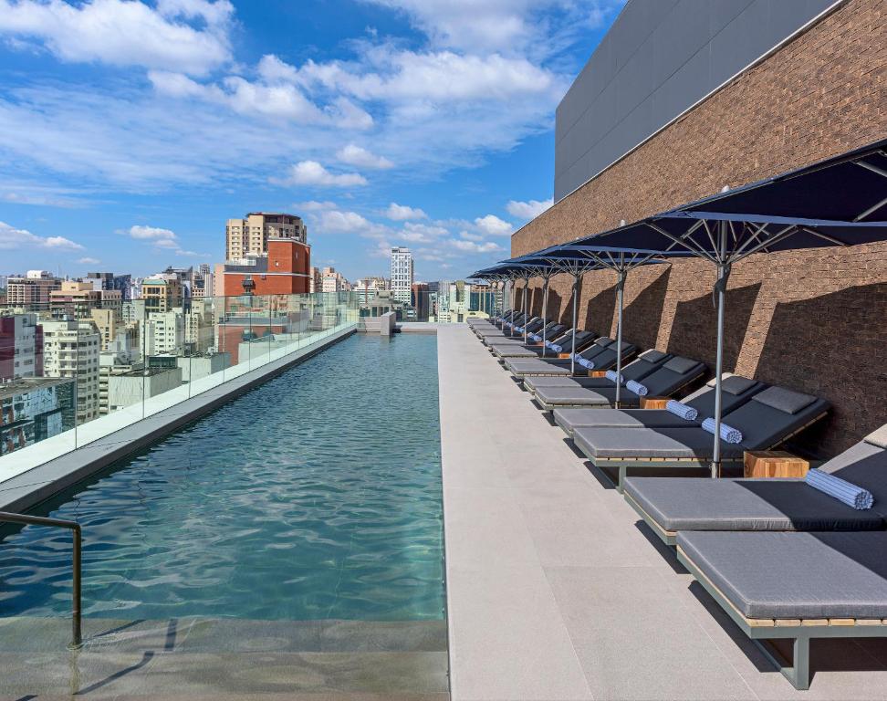 a pool on the roof of a building with lounge chairs at Fasano Sao Paulo Itaim in Sao Paulo
