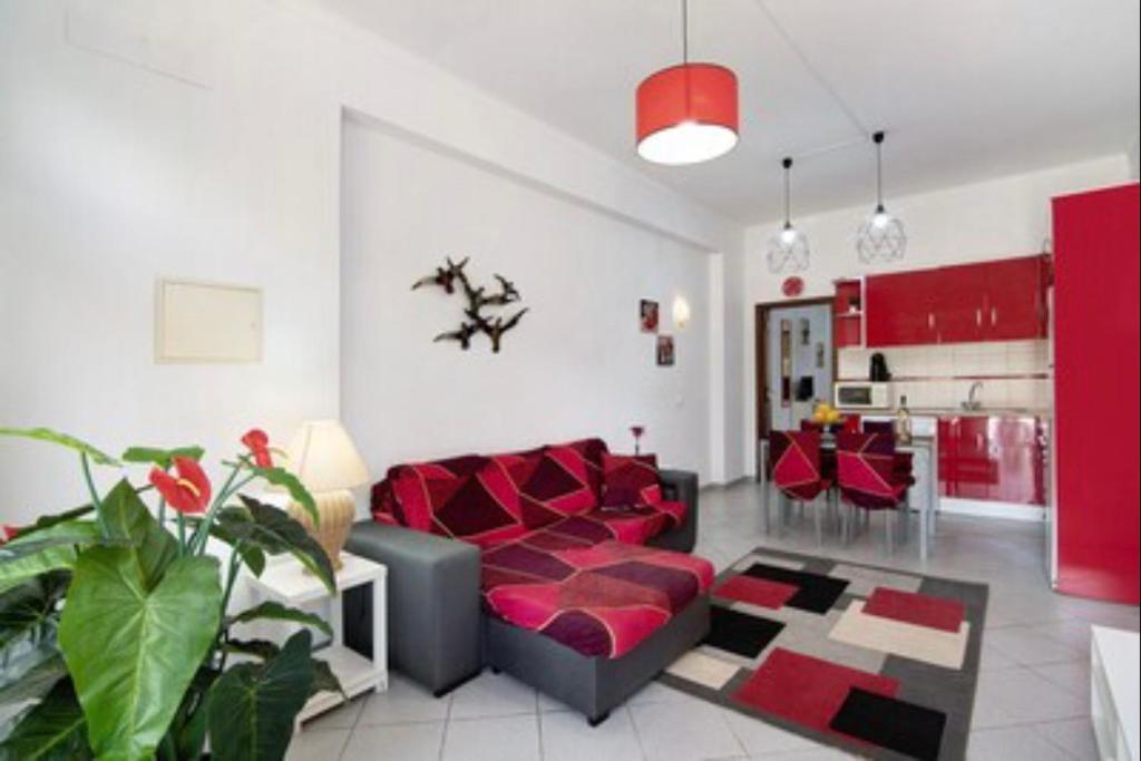 ein Wohnzimmer mit einem roten Sofa und einer Küche in der Unterkunft Apartamentos Paradise Fuseta in Fuseta