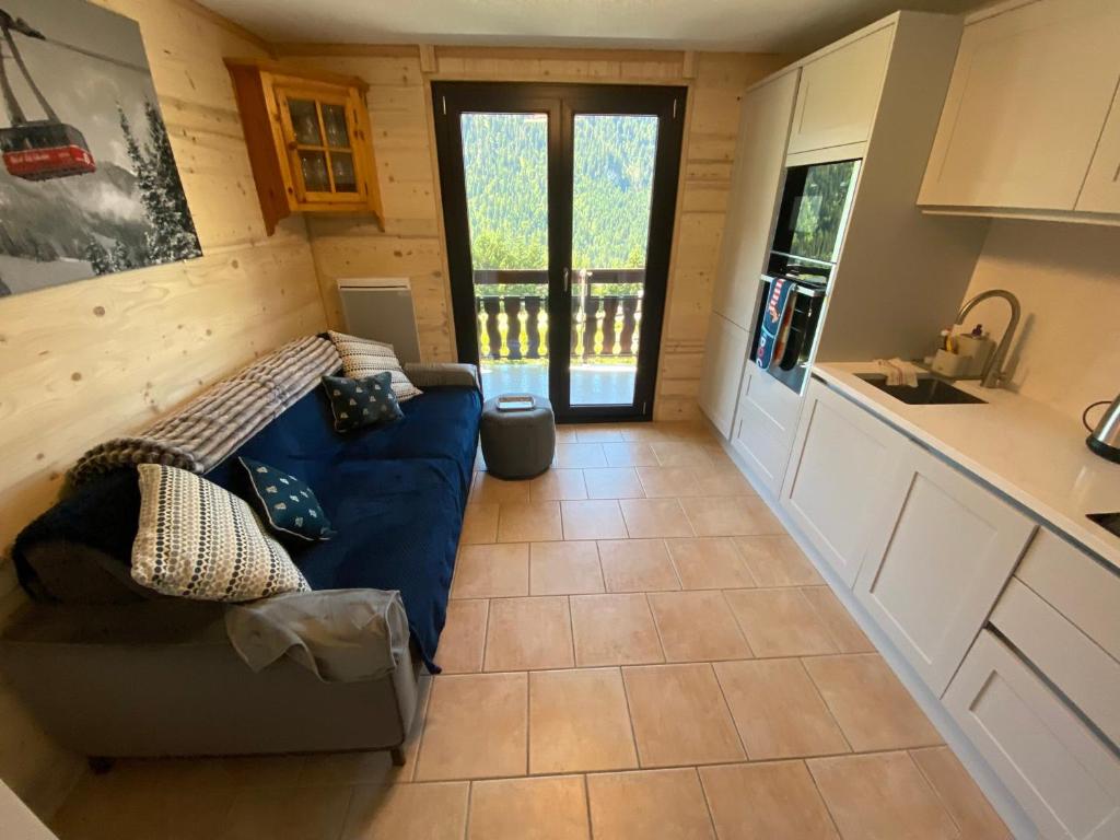 un salon avec un canapé bleu dans une cuisine dans l'établissement Appartement cosy à Châtel avec parking privé, proche centre et télécabine. Animaux non admis. - FR-1-693-45, à Châtel