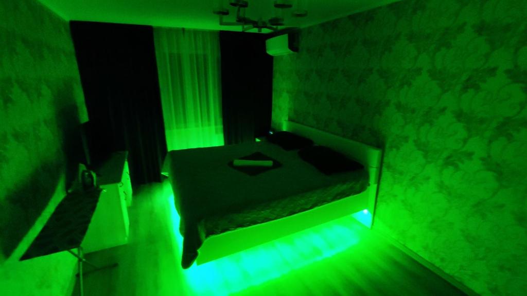 Luz verde en una habitación con cama en Домашний уют в центре, en Uralsk