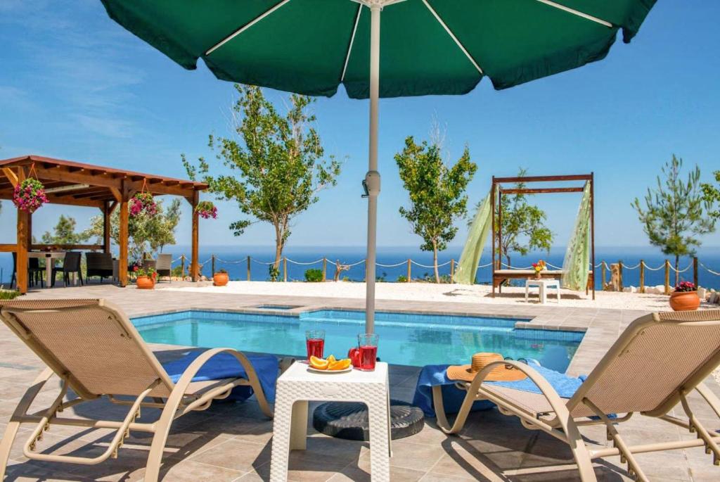 a swimming pool with two chairs and an umbrella at Villa Paradiso Sunset in Pomos